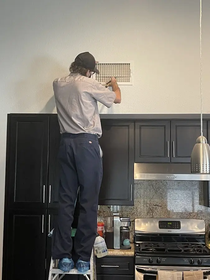Technician inspecting an air vent during HVAC service in Cornelius